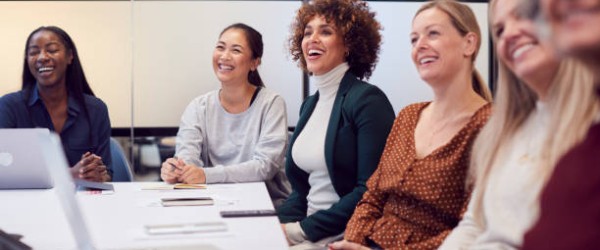 Line Of Businesswomen In Modern Office Listening To Presentation By Colleague